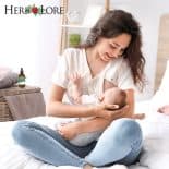 Smiling mother breastfeeding her baby in a cozy bedroom with Herb Lore Goat’s Rue Tincture bottle visible on a nearby table