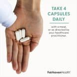 Hand holding four white capsules of Fairhaven Health Myo + D-Chiro Inositol with dosage instructions to take daily with a meal